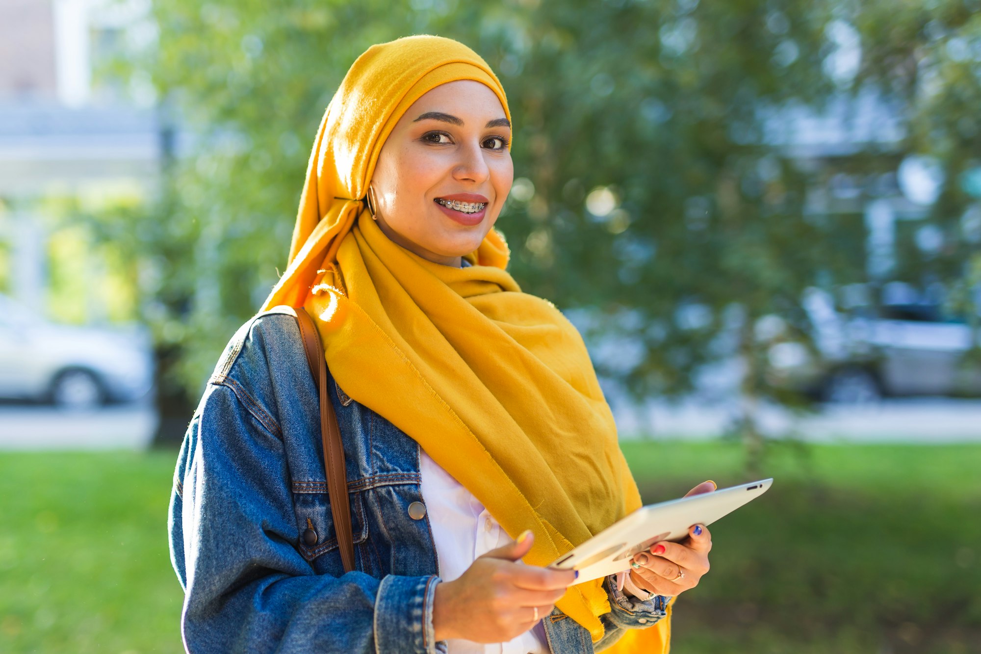 Arab woman student. Beautiful muslim female student wearing bright yellow hijab holding tablet