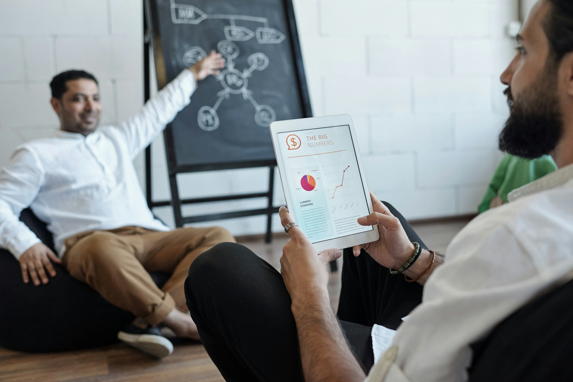 Bearded Arabic businessman with tablet listening to coach